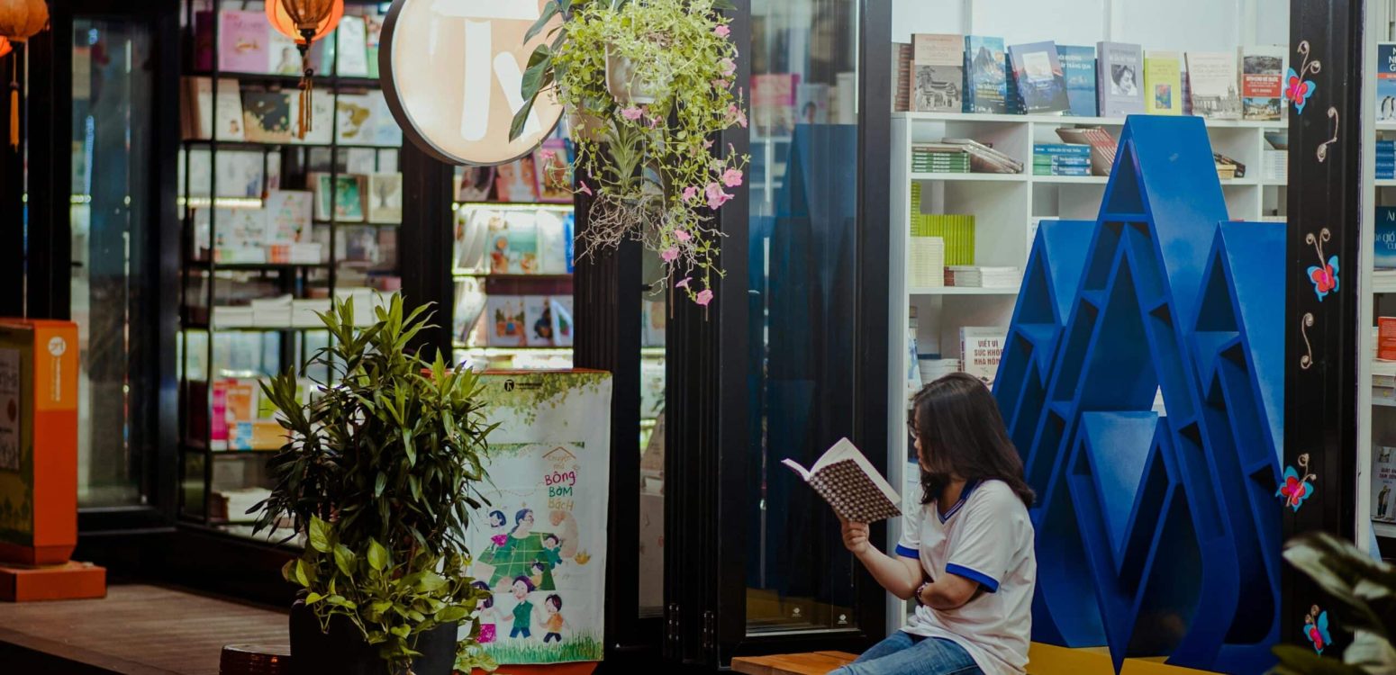 Girl reading a book in front of a bookstore, discovering new ideas and creativity